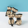 Chaussures imperméables antidérapantes pour chien, lot de 4 beiges à motif pattes noires, posées sur fond bleu et blanc