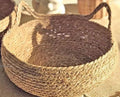 Panier nid en herbe tressée vu de près : bord torsadé et oreilles tressées